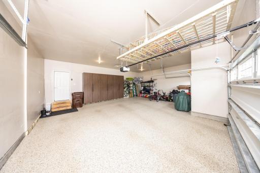 Insulated three-car garage featuring epoxy floors, premium built-in cabinetry, and many custom storage racks