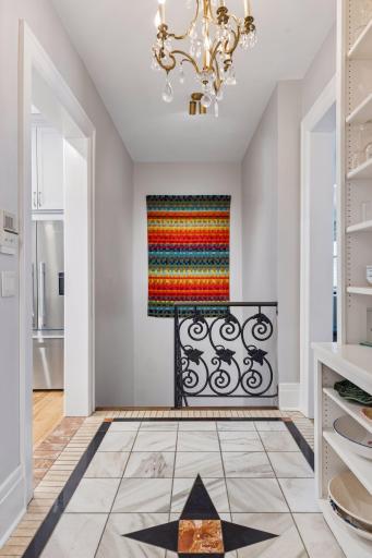 Staircase to lower level featuring custom metalwork, view from pantry