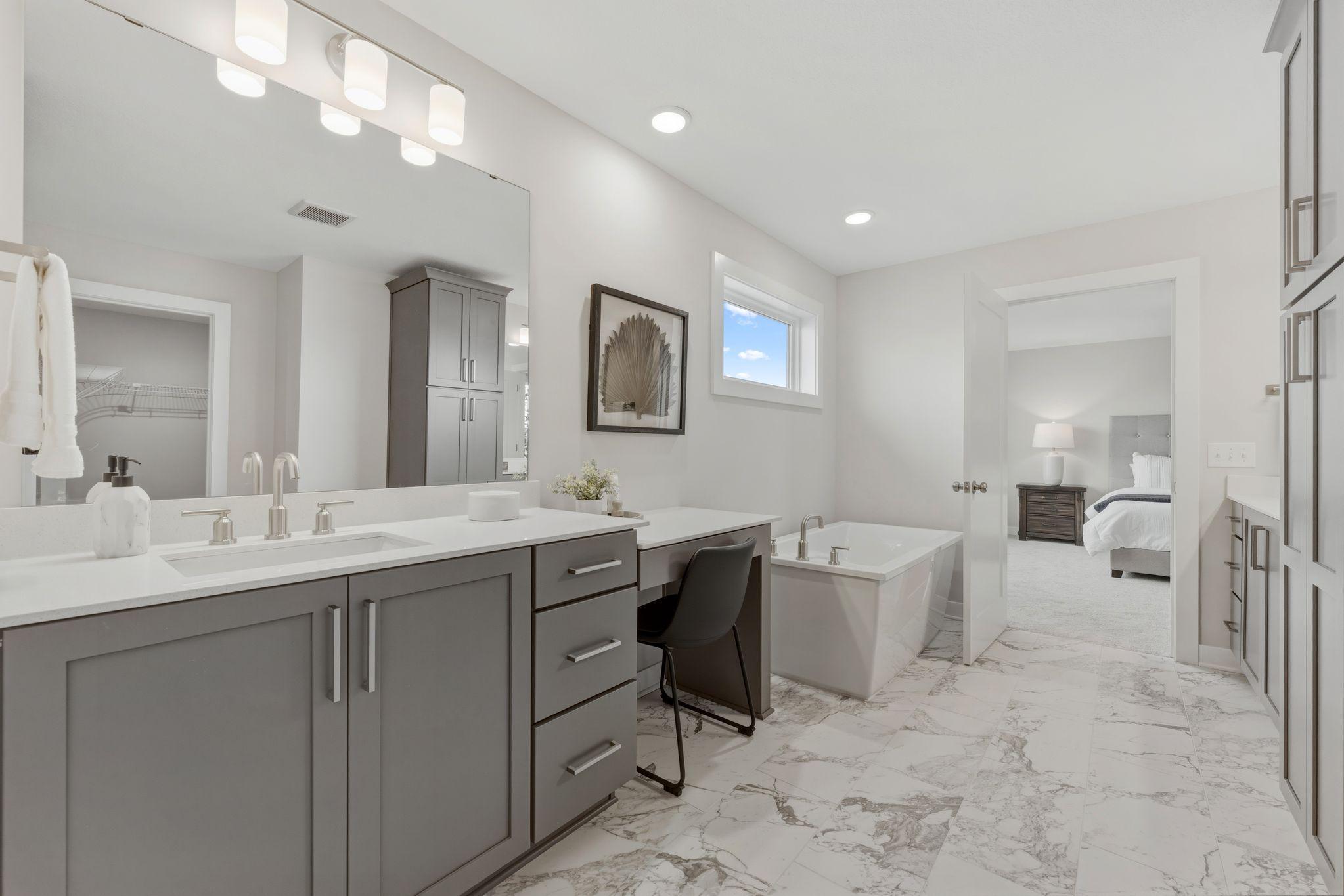 Primary bedroom ensuite with separate dual vanities, fully tiled walk-in shower, freestanding soaker tub and his/hers closet sides