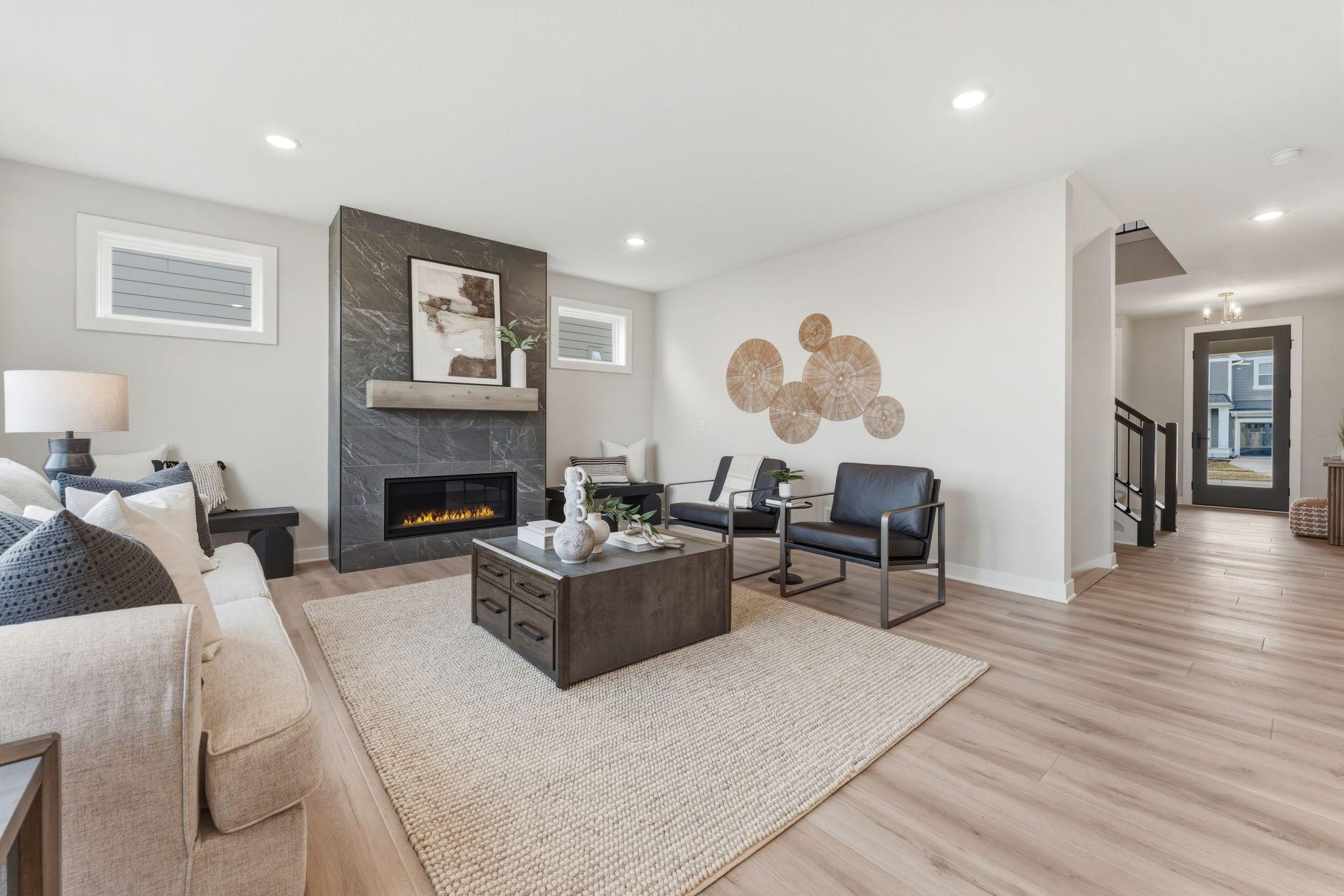 Living room with fully tiled gas fireplace overlooked by kitchen