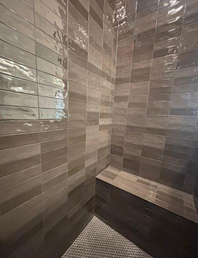 Dramatic and gorgeous walk-in tiled shower with bench