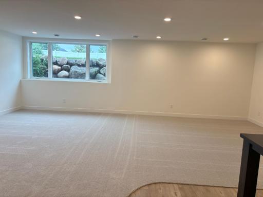 Lower level family room with enlarged three pane window and boulder retaining wall