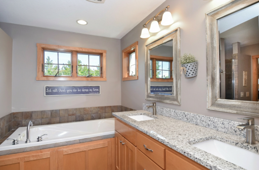 Primary bath with double sinks, jetted tub, separate shower, and heated floors