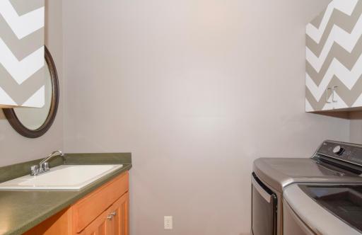 Main floor laundry room with cabinets and sink