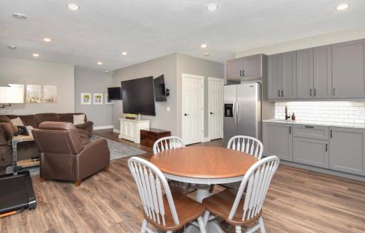 Lower level kitchette/wet bar with full-sized stainless steel refrigerator, sink, tile backsplash, undercabinet lighting, and cabinets