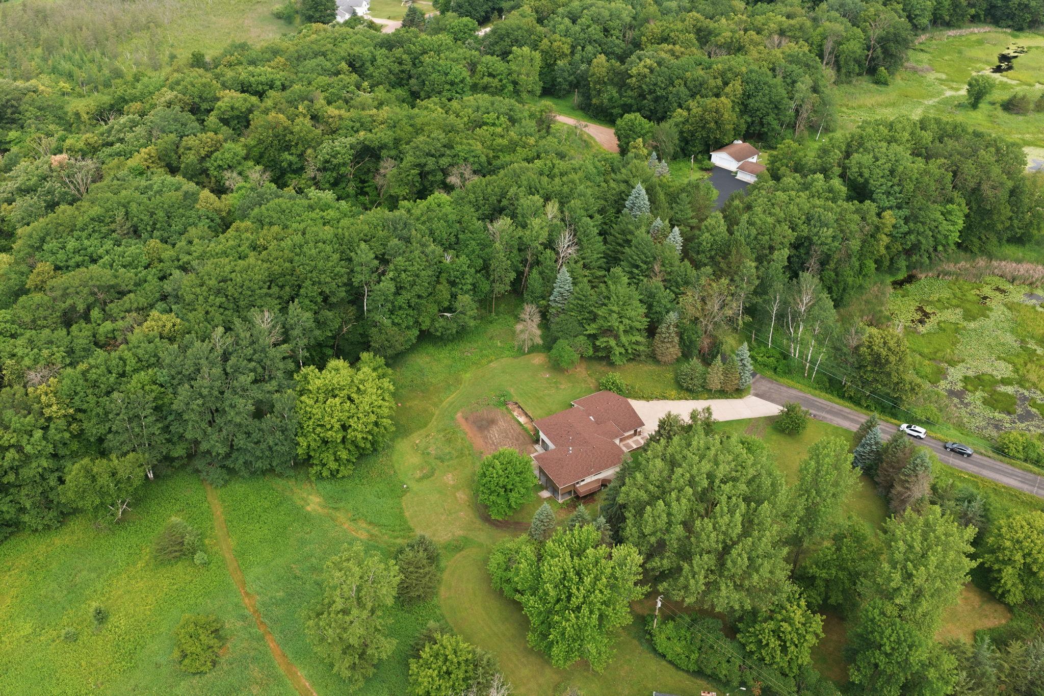 The property line follows the lighter green mown grass areas into the woods at the top of the photo in this shot.