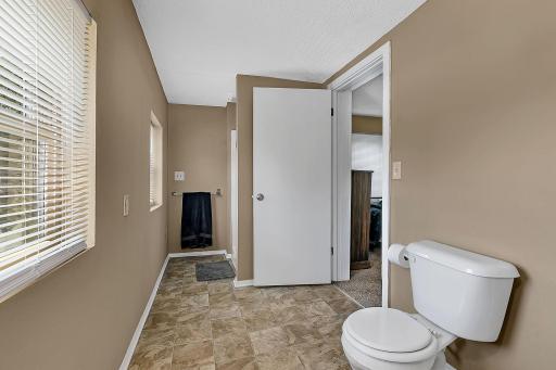 Upstairs 3/4 bathroom with walk-through open door to the primary bedroom in the background. Shower entrance to the right of the towel bar.