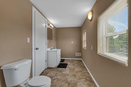 Another view of the large, 3/4, upstairs bathroom from the shower end. The door between the toilet and vanity leads to the upstairs family room. New blinds!