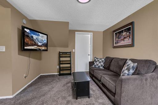 This is the upstairs family room with fresh paint and new carpeting. The door to the rear is one of the entrances to the upstairs bathroom. The wall mounted, flat screen TV, conveys with the property. Functioning at time of listing but not warranted