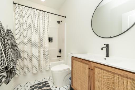 Modern vanity, matte black fixtures, and a tub/shower combination on the main floor