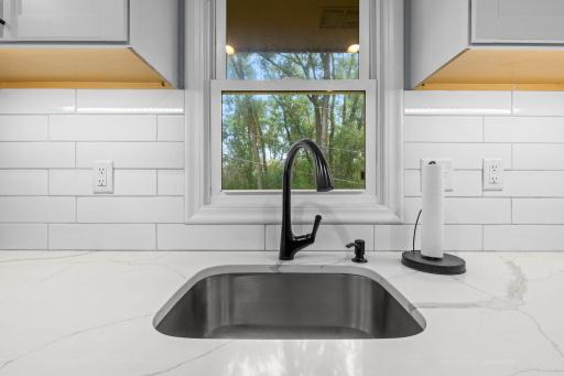 Kitchen sink has a beautiful window looking out at the wooded backyard