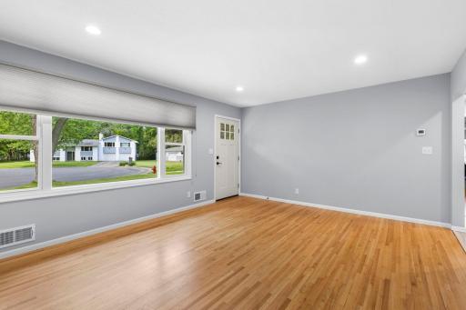 Living room has a large window offering tons of natural light and hardwood floors