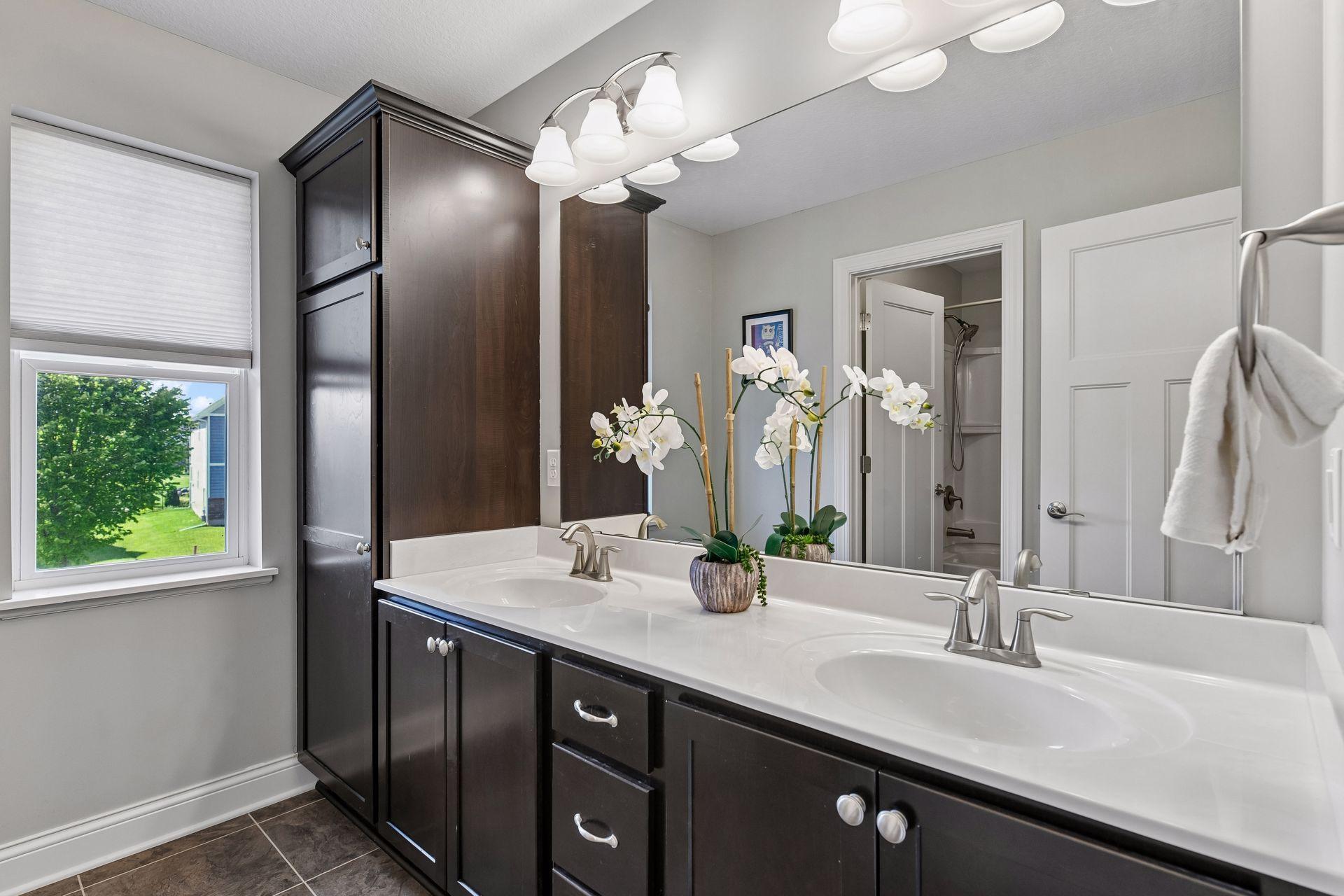 Primary bath with a double vanity, tall linen storage, and separate door to shower space.