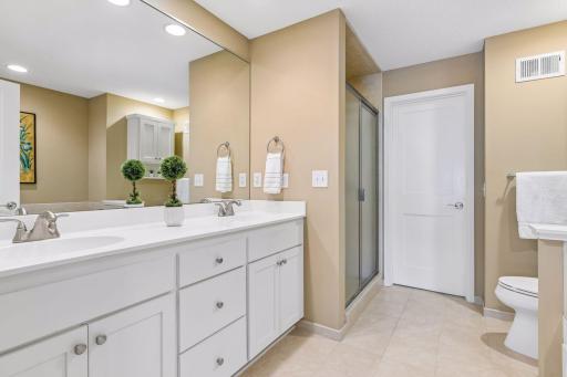 The primary bathroom features dual sinks, abundant storage, a walk-in shower and separate soaking tub (not shown). Behind the closed door is the walk-in closet.