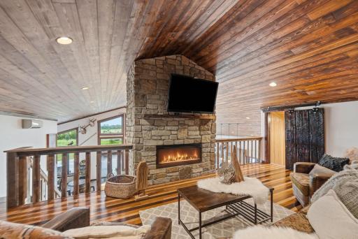 The expansive loft provides additional sleeping accommodations, a cozy fireplace, and panoramic views overlooking the great room and surrounding landscape