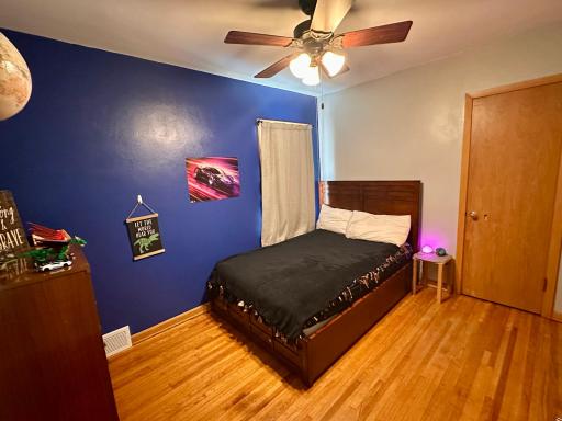 Bedroom #1 on main floor features original hardwood flooring and a ceiling fan.
