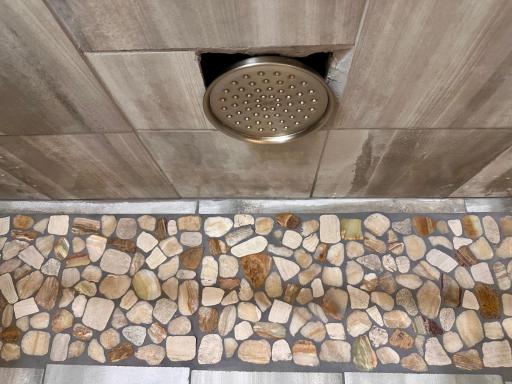 Impressive detail highlights the rain shower head in ceiling of lower level bath.