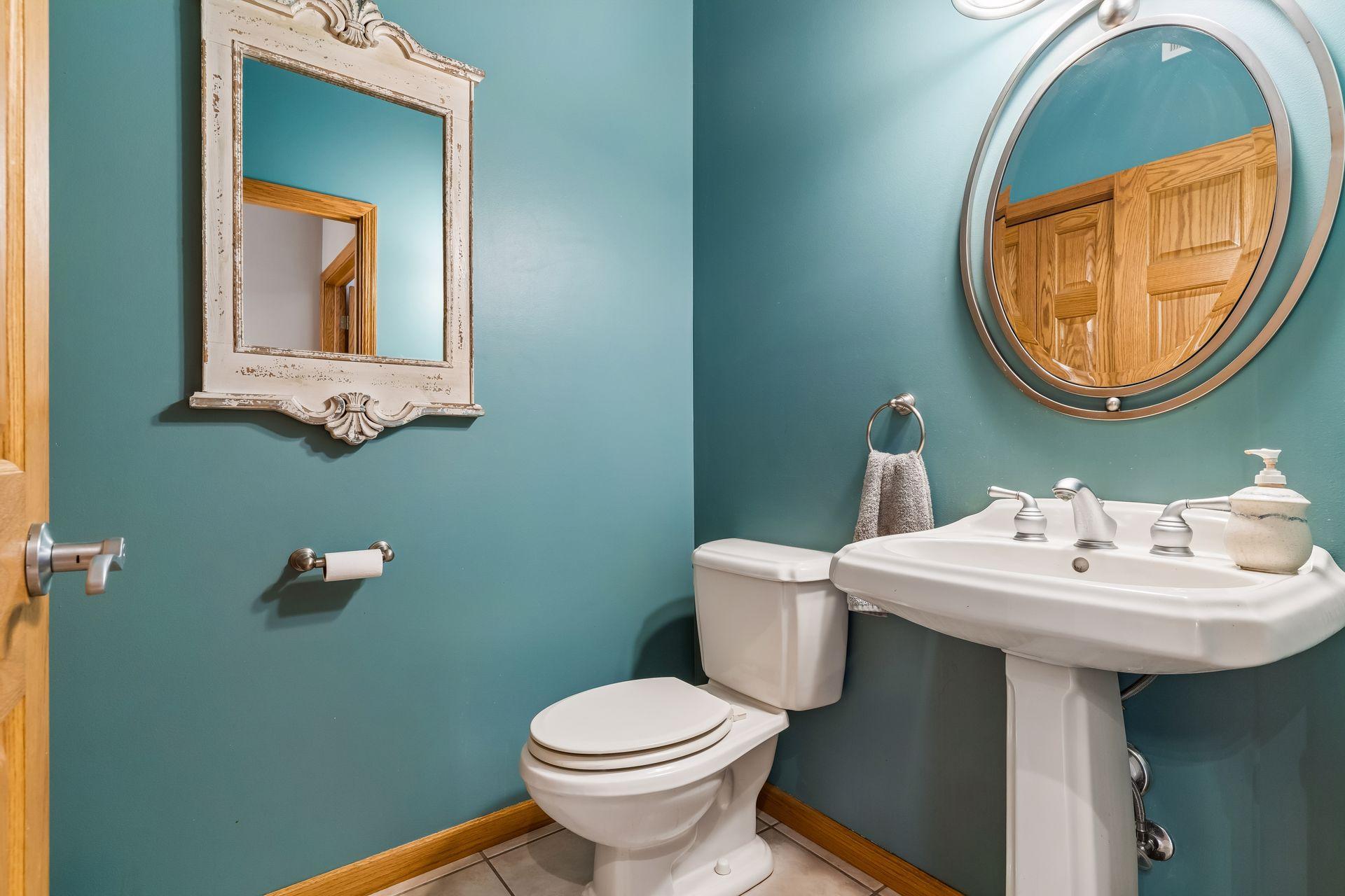 The main-level half bath provides both style and function with tile flooring, a classic pedestal sink, and a linen closet for storage.