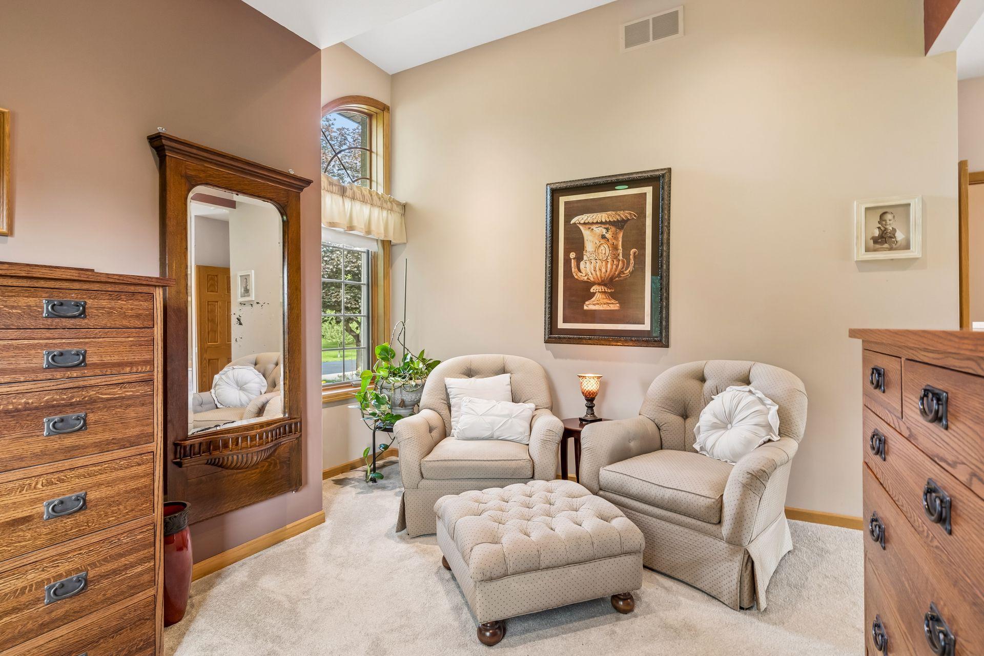 Another view of the primary suite highlights a versatile sitting area, abundant natural light, and impressive ceiling height, offering a spacious and serene retreat within the home.