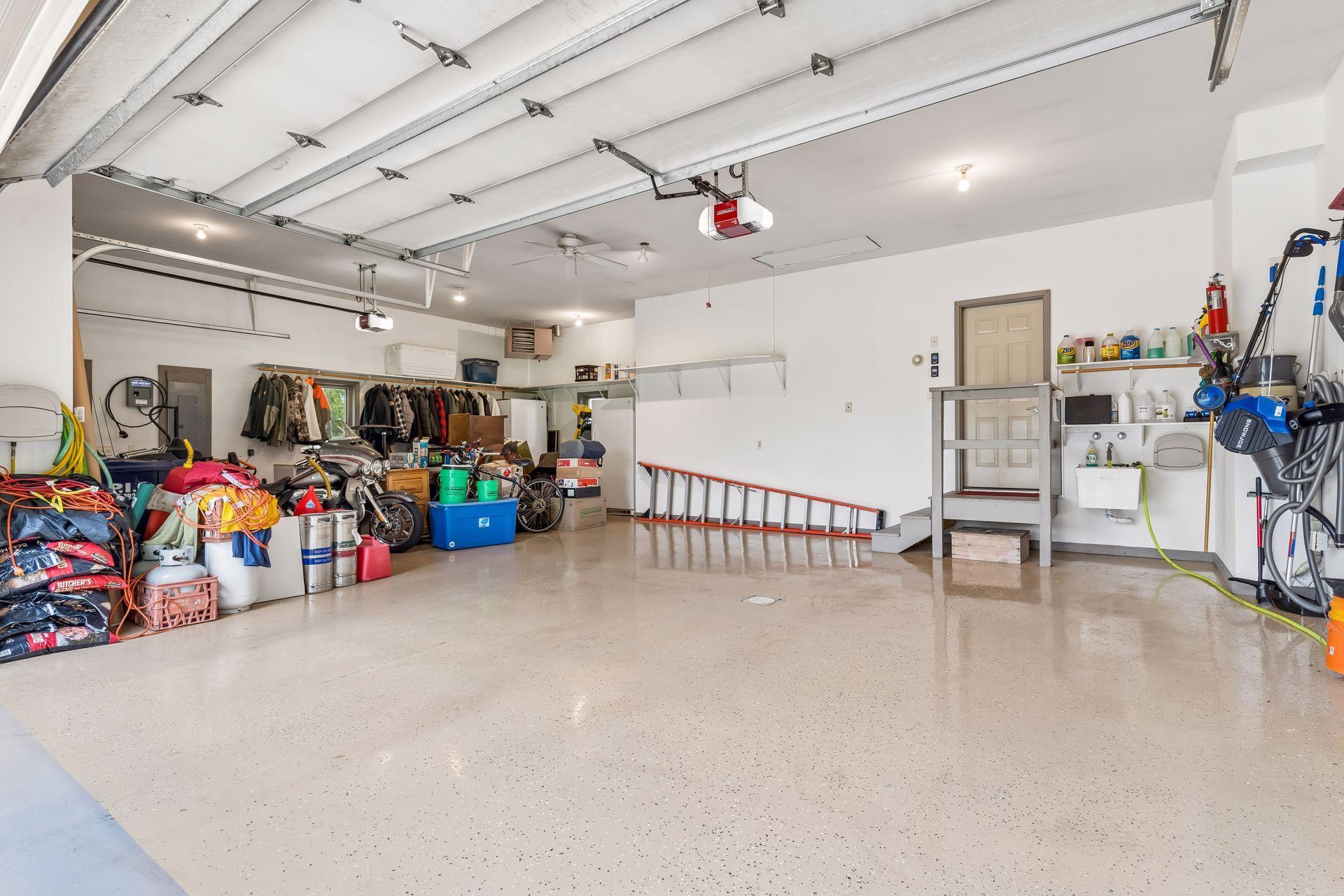 The spacious main level three-car garage is thoughtfully equipped with an epoxy floor, furnace heat, and hot and cold water access, offering exceptional functionality for vehicles, hobbies, and projects.