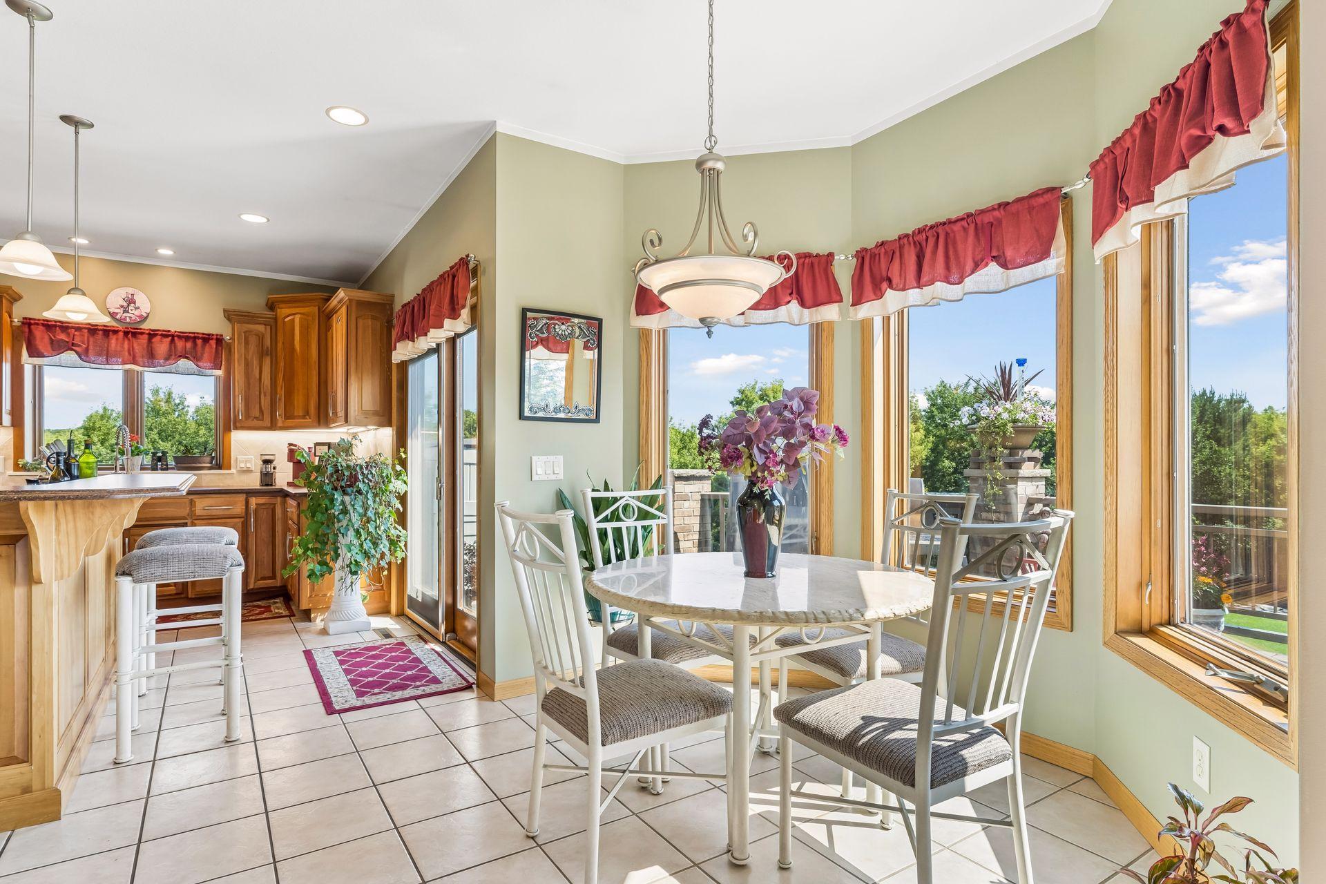 The dining space offers a seamless connection to the kitchen, highlighted by chandelier lighting, three bay windows, and heated tile flooring for year-round comfort.