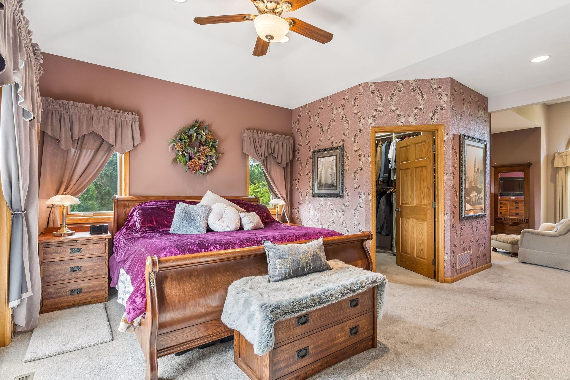 This additional perspective of the primary bedroom highlights the generous walk-in closet, ceiling fan with integrated lighting, recessed lights, and a spacious layout.