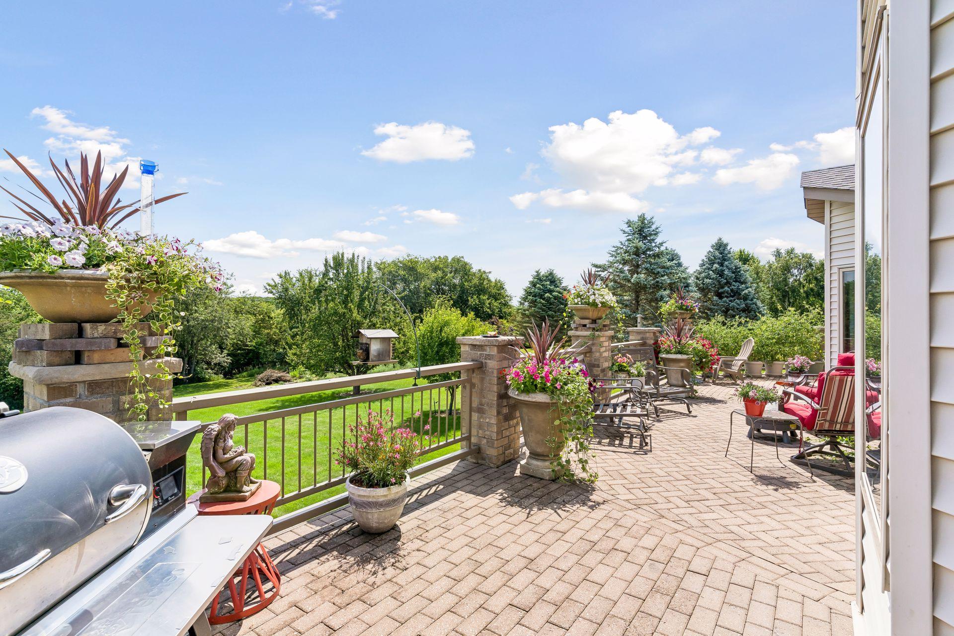 An impressive outdoor retreat awaits with this expansive high-end deck featuring a steel frame, elegant brick pillars, paver stone decking, and integrated lighting that extends the entire length of the home.