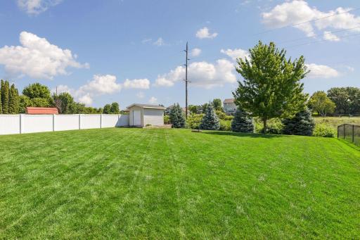 Manicured back yard with storage shed and fencing on two sides
