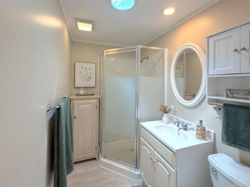 The beautifully updated bathroom features a spacious corner shower, modern fixtures, and clean finishes that complement the cabin's fresh, remodeled design.