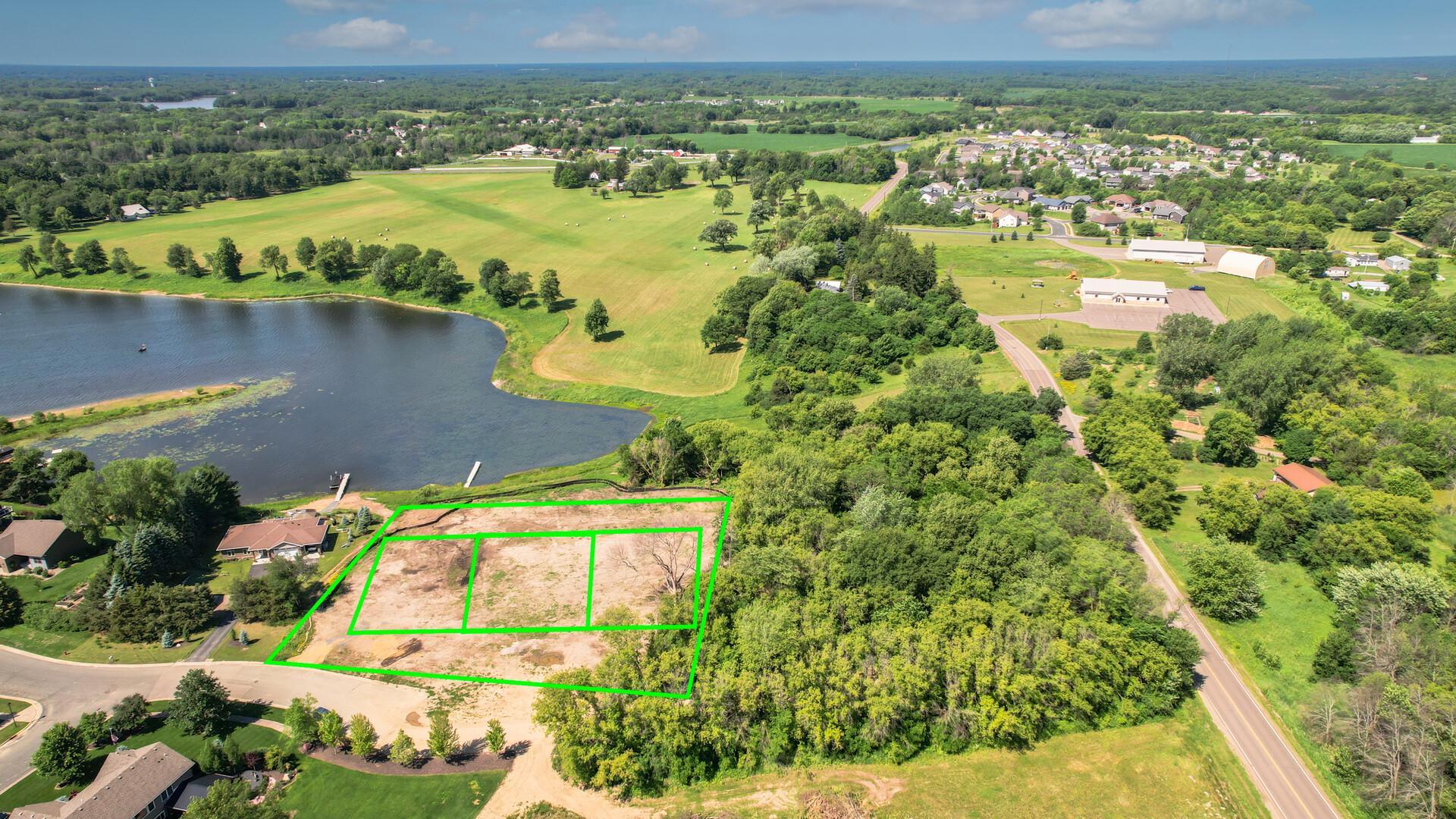 AI generated view from the road side of the lot. The Seller will be removing all the lake weeds and installing a larger dock for 3 boats. This has been edited to remove the current lake weeds.