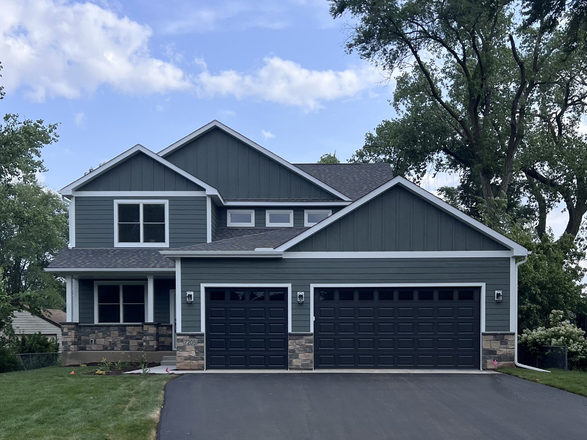 Front view showing finished landscaping, front porch & 3-car garage
