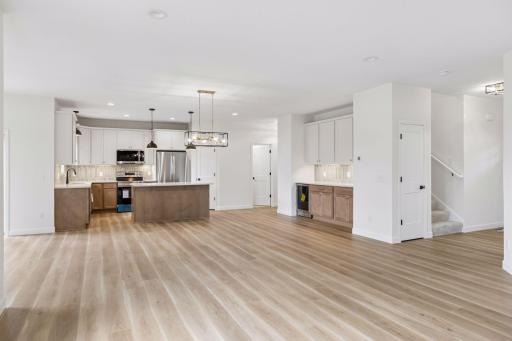 Full view of kitchen, extra cabinets to right with beverage frig and stairs to upper level on right