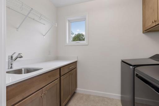 Laundry with black matte washer_dryer, cabinets, shelving, sink and window