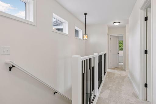 Upper level hall with banister and natural light from transom windows on left
