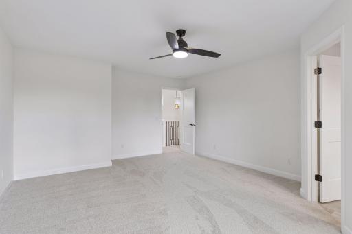 Primary bedroom includes plush carpet and ceiling fan