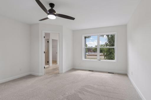 Primary bedroom with large windows and ceiling fan