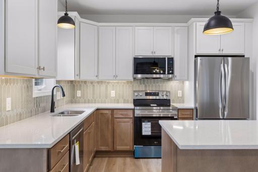 Kitchen offers plenty of lighting and style with tiled backsplash and under cabinet lighting