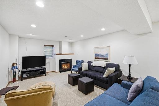 The finished lower-level family room offers a warm and inviting retreat with a cozy gas fireplace, recessed lighting, and generous space for movie nights, game days, or entertaining family and friends.