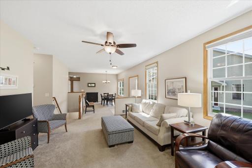 Spacious open-concept living room featuring soaring ceilings, abundant natural light, a cozy gas fireplace, and seamless flow to the dining areaâperfect for everyday living and entertaining.