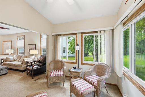 The inviting four-season sunroom seamlessly extends the main living space, creating the perfect spot to relax while enjoying abundant natural light and peaceful views of the surrounding green space.