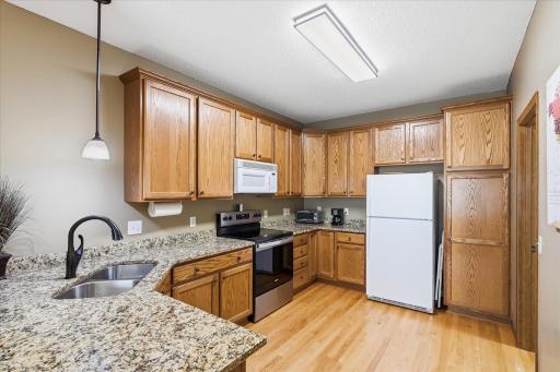 The well-appointed kitchen features granite countertops, hardwood floors, abundant cabinetry, and an efficient layout designed for both everyday living and effortless meal preparation.