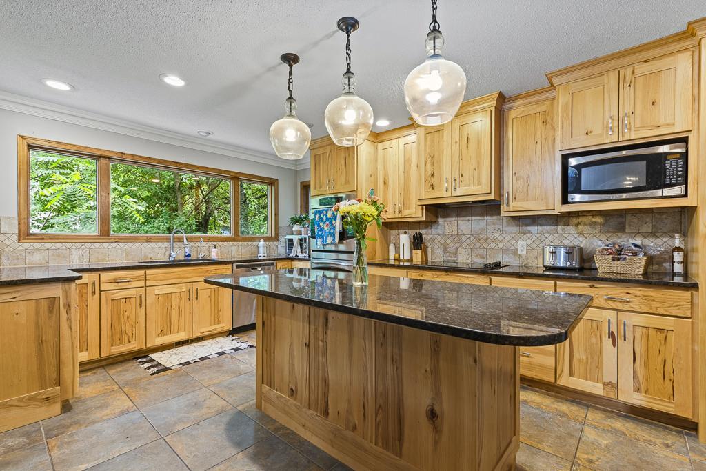 Absolutely stunning kitchen with tile backsplash, hickory cabinets, granite countertops, and abundance of counterspace