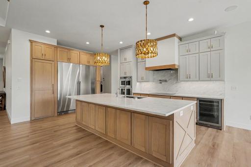 Stunning chef's kitchen with an oversized quartz island, custom cabinetry, premium built-in appliances, and designer pendant lighting.