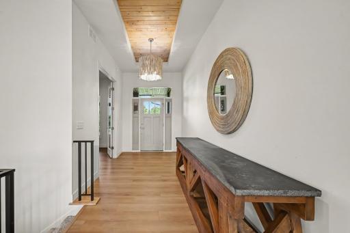 Impressive front foyer featuring a striking wood-planked ceiling, designer chandelier, and warm, welcoming architectural details.