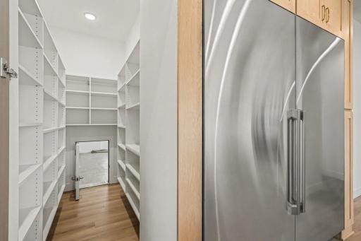 Spacious walk-in pantry with sensor lighting and custom built-in shelving. Notice the small door in back of pantry that opens to the garage so that you can take groceries from your car and instantly slide them into the pantry for storage!
