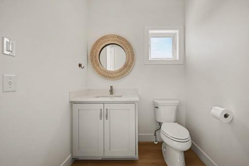 Elegant main-level powder room off of the 4 season porch featuring a quartz vanity, designer fixtures, and timeless finishes. A very large walk-in storage closet is connected to this bathroom.