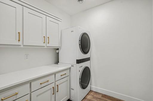 Convenient lower-level laundry room featuring custom cabinetry, folding counter, and additional storage for effortless household organization.