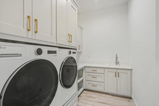 Well-designed main-level laundry room with custom cabinetry, folding counter, utility sink, and exceptional storage.
