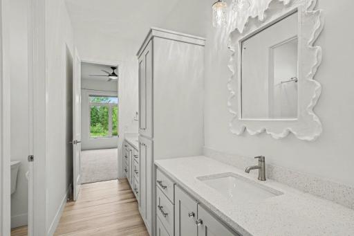 Elegant Jack-and-Jill bathroom featuring dual vanities, quartz countertops, custom cabinetry, and designer lighting.