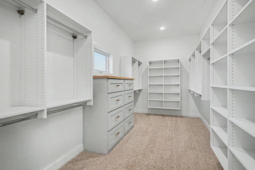 Expansive custom walk-in closet featuring built-in cabinetry, dresser storage, abundant shelving, and thoughtfully designed organization.